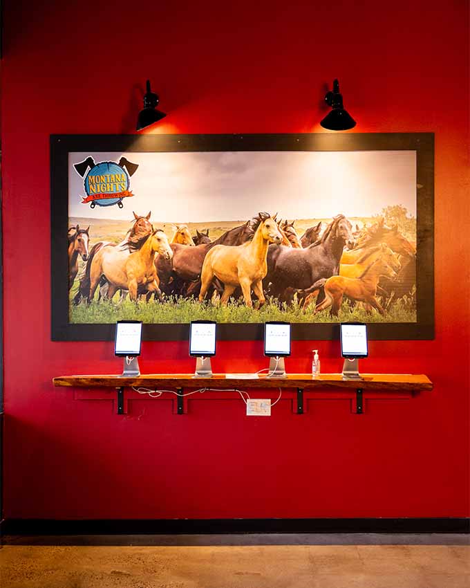 Framed photograph of wild ranging horses above check-in tablets. Montana Nights event space. Montana Nights Top Axe-Bar + Entertainment Center in CT