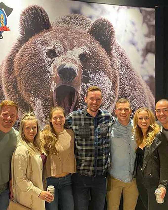 Happy group behind bear growling mural at Montana Nights Top Axe-Bar + Entertainment Center in CT