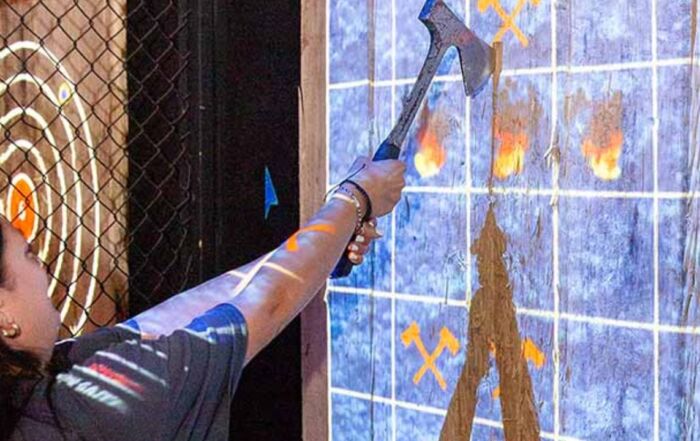 woman aiming an axe at a projected target on a wooden board.