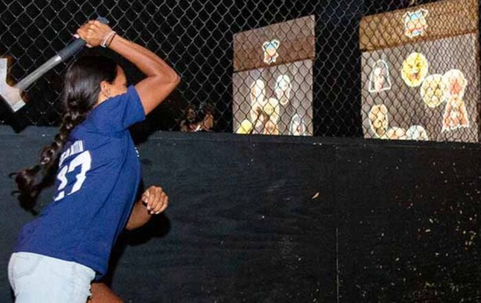 Woman throwing an axe at a wooden target at Montana Nights Axe Throwing.