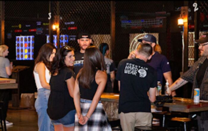 A group of diverse individuals socializing around a bar, engaged in conversation and enjoying drinks together. 