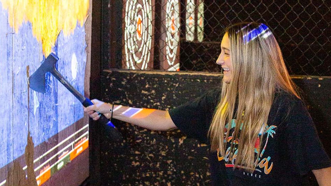 A girl throwing axe on the axe throwing target.