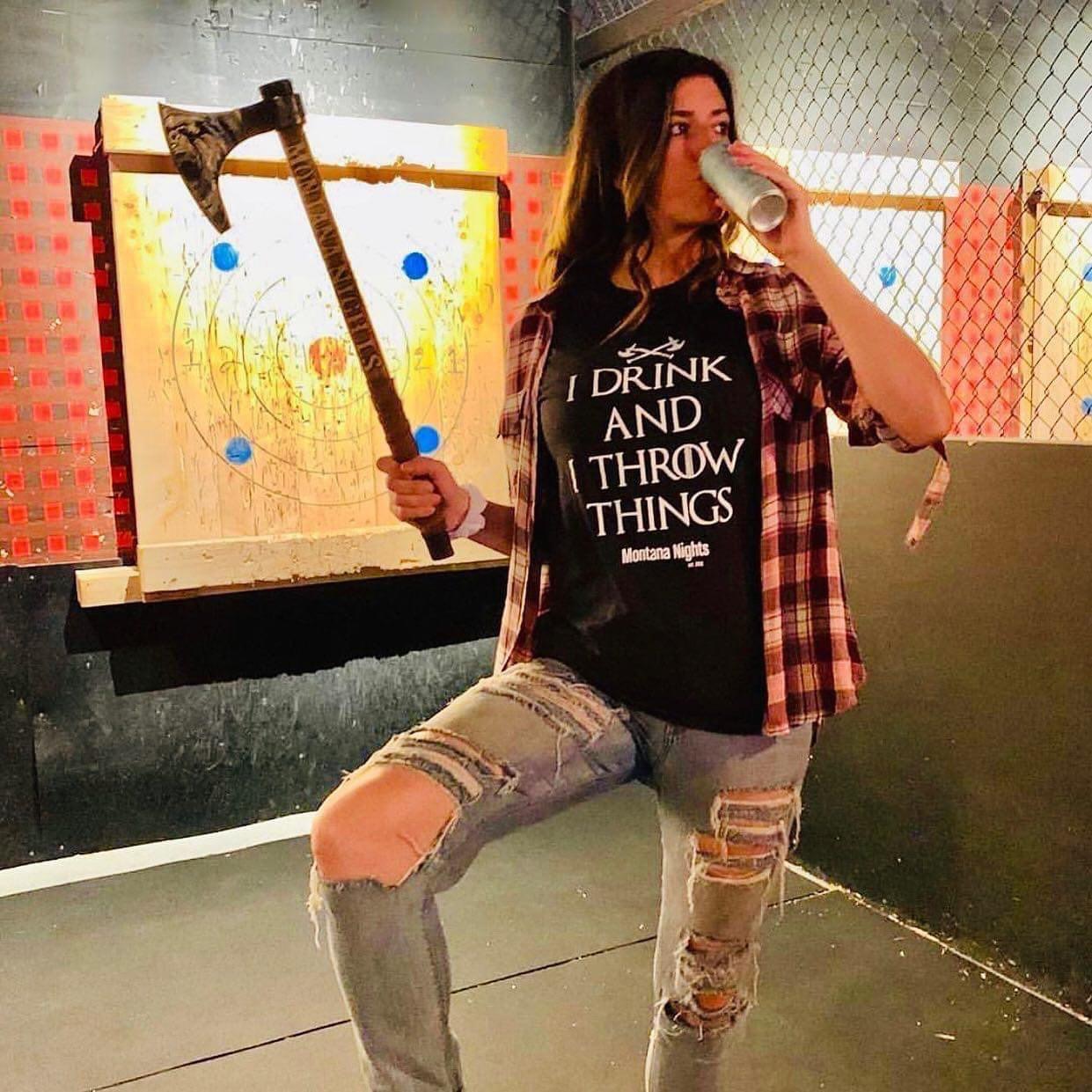Woman holding an axe at Montana Nights’ axe throwing lane with a wooden target in the background.