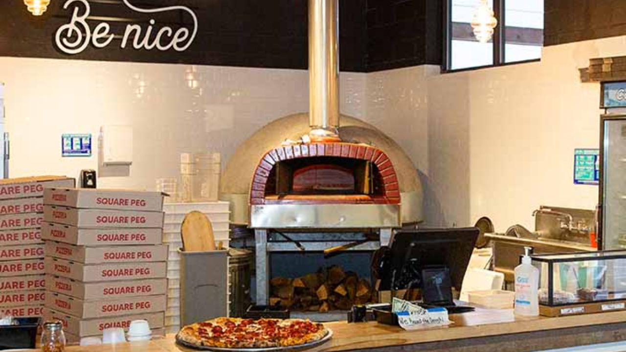 Montana Nights featuring a wood-fired pizza oven, stacked pizza boxes, and a freshly baked pizza on the counter