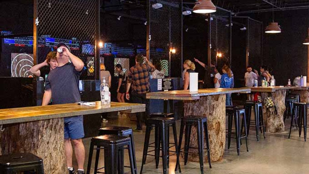 Wide view of Montana Nights, Newington with multiple lanes, wooden tables, bar stools, and people practicing throws
