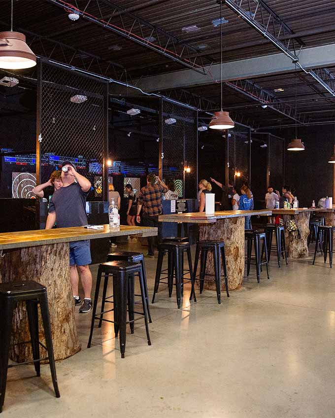 Indoor axe throwing venue with multiple lanes and wooden tables at Montana Nights.