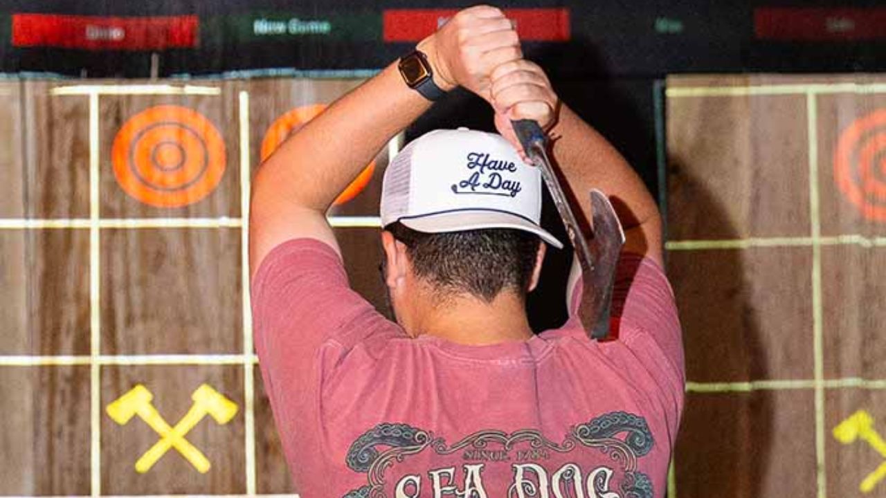 Man holding an axe facing a digital scoring target board at Montana Nights Newington