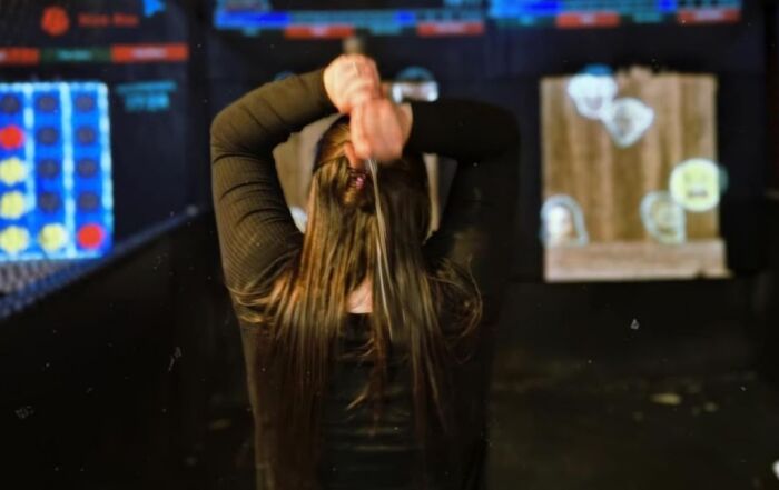 Woman preparing to throw an axe at an indoor target range