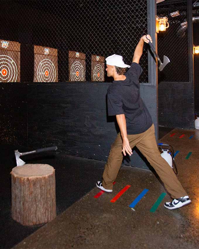 Man throwing axe toward wooden targets in indoor axe throwing range at Montana Nights.
