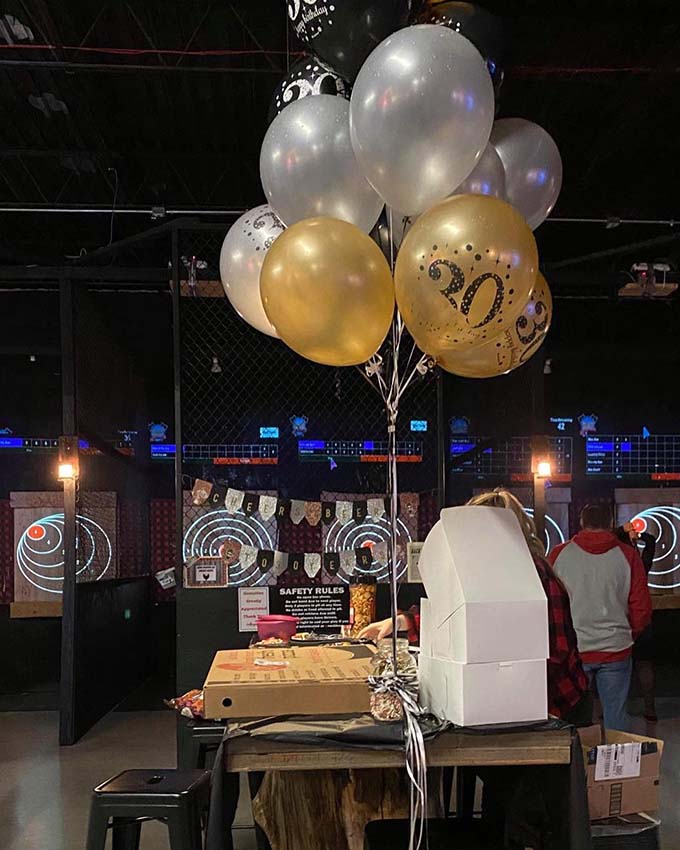 Birthday party setup with gold and silver balloons and table decorations indoors.