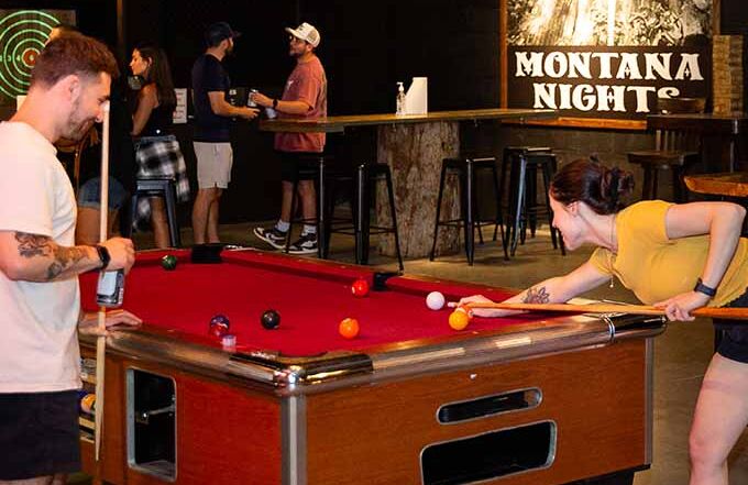 Adults playing pool at Montana Nights axe throwing venue