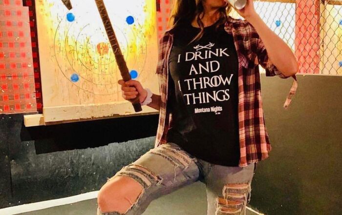 Casual axe throwing experience with woman holding axe near target