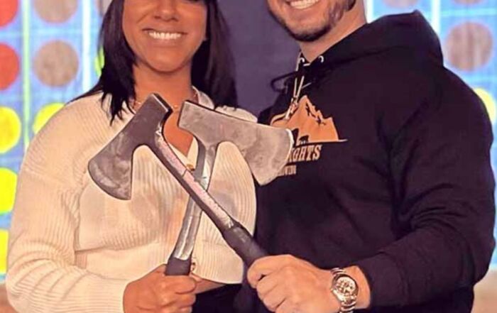 Couple holding axes at axe throwing game indoor venue Montana Nights