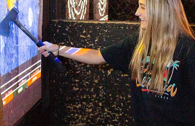 Woman enjoying indoor axe throwing game with interactive targets
