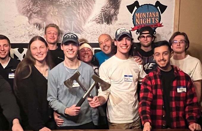 Group of friends posing with axes before their axe throwing session at Montana Nights Axe Throwing.