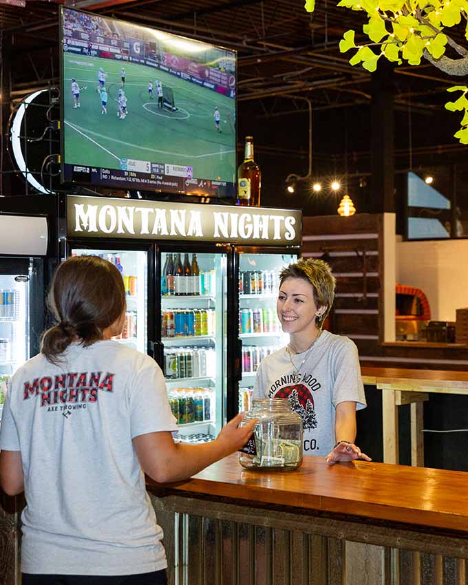 Guests ordering drinks and relaxing at the bar inside Montana Nights Axe Throwing.