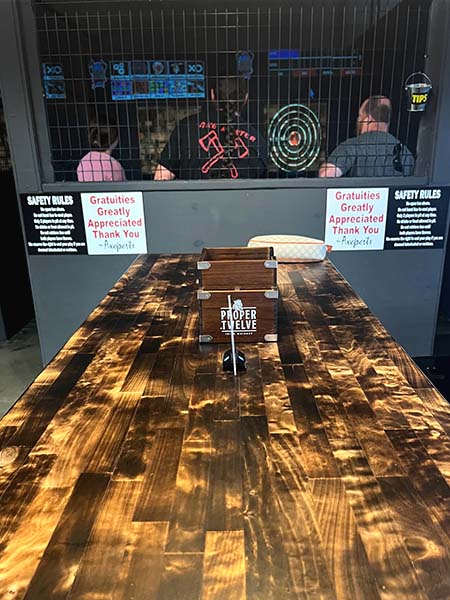 Indoor axe throwing lanes at Montana Nights Putnam with digital targets and wooden seating area