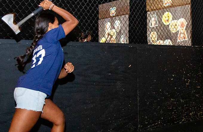 Woman throwing an axe at indoor target lanes during axe throwing game