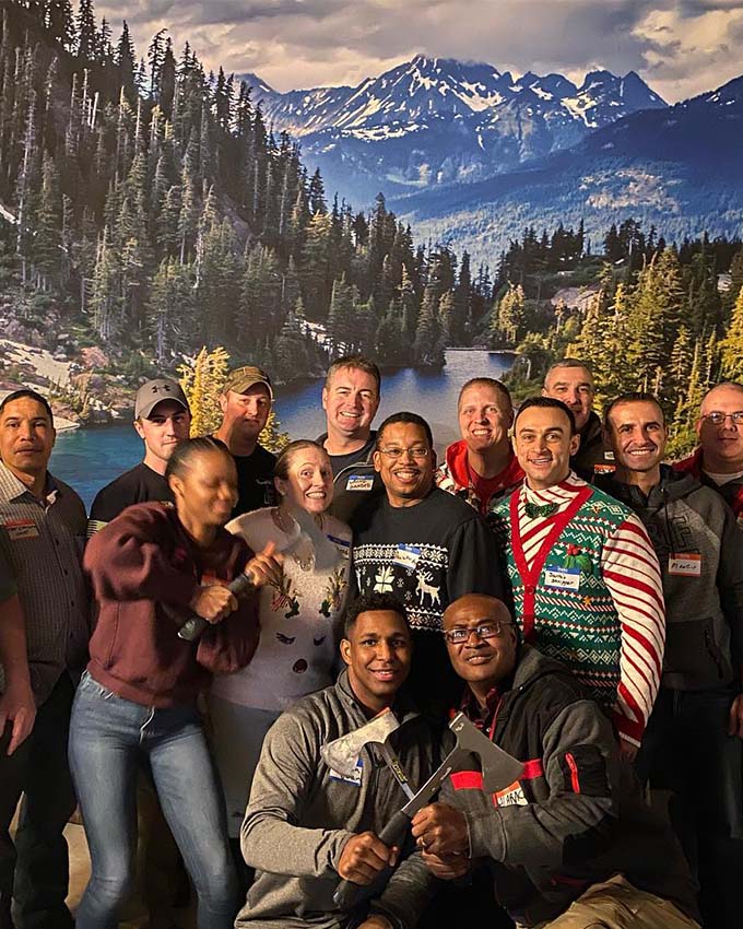 Group of friends posing together during a holiday party and axe throwing event at Montana Nights.