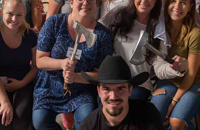 Group of friends posing with axes after an axe throwing event at Montana Nights.