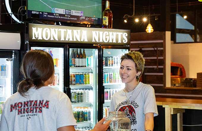 Guest checking in at the Montana Nights reception and bar area before an axe throwing session.
