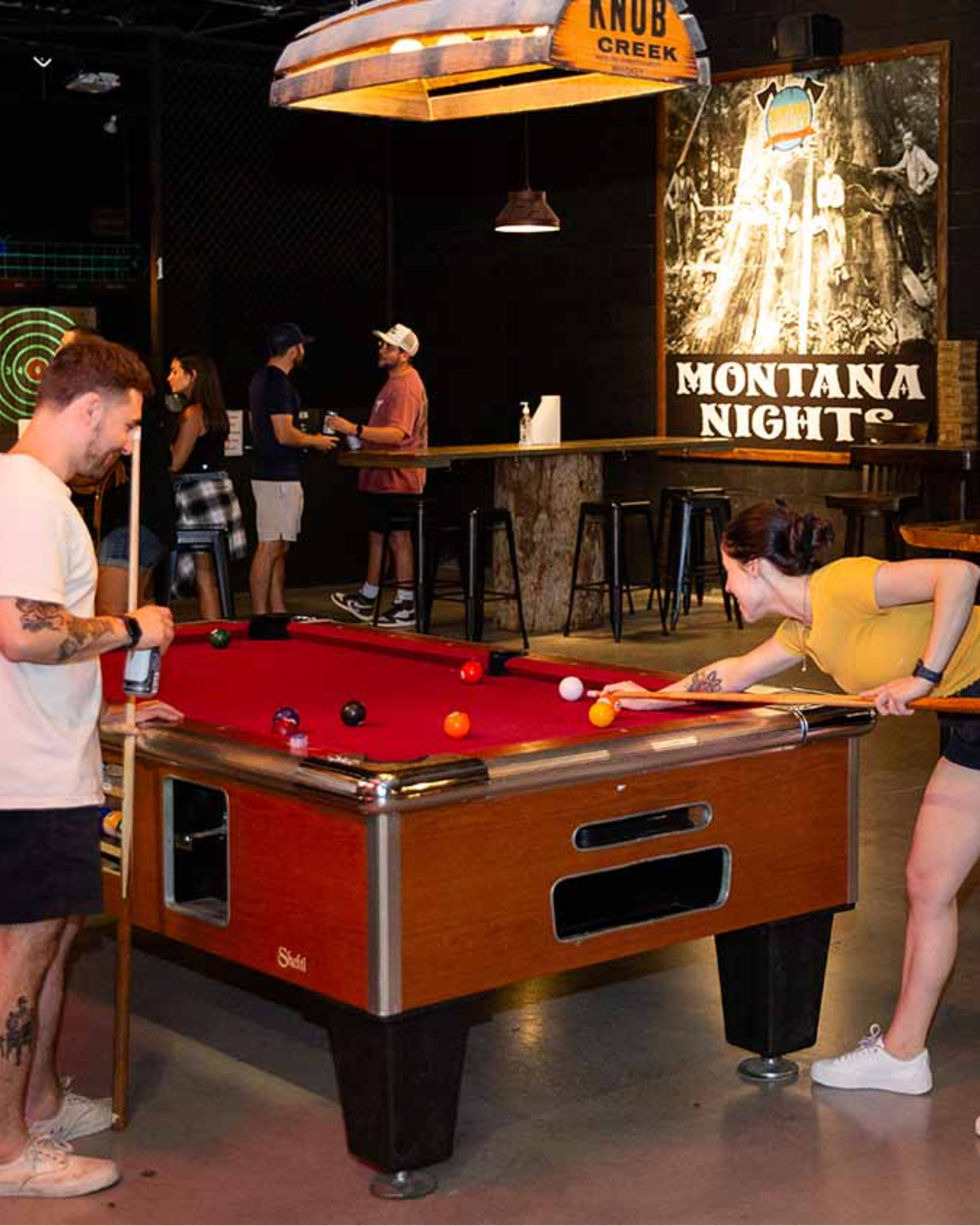 Guests playing pool and relaxing inside Montana Nights Axe Throwing
