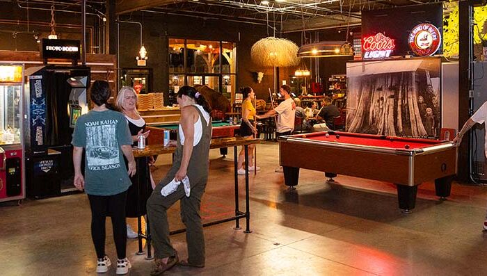 People enjoying arcade games, pool tables, and social activities inside Montana Nights Axe Throwing venue.