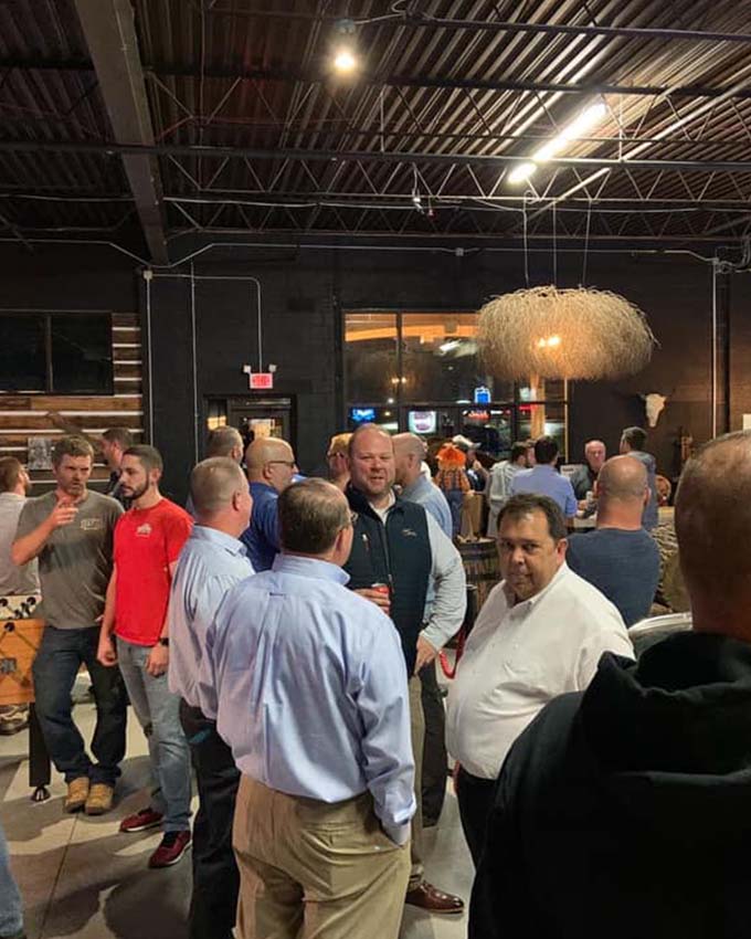 Professionals networking and socializing during a retirement party at Montana Nights Axe Throwing venue.