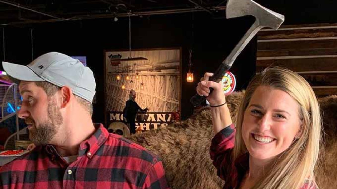 Couple posing with axes during a fun axe-throwing date night.
