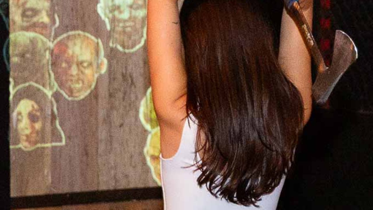  Woman preparing to throw an axe at an interactive digital target at Montana Nights. 