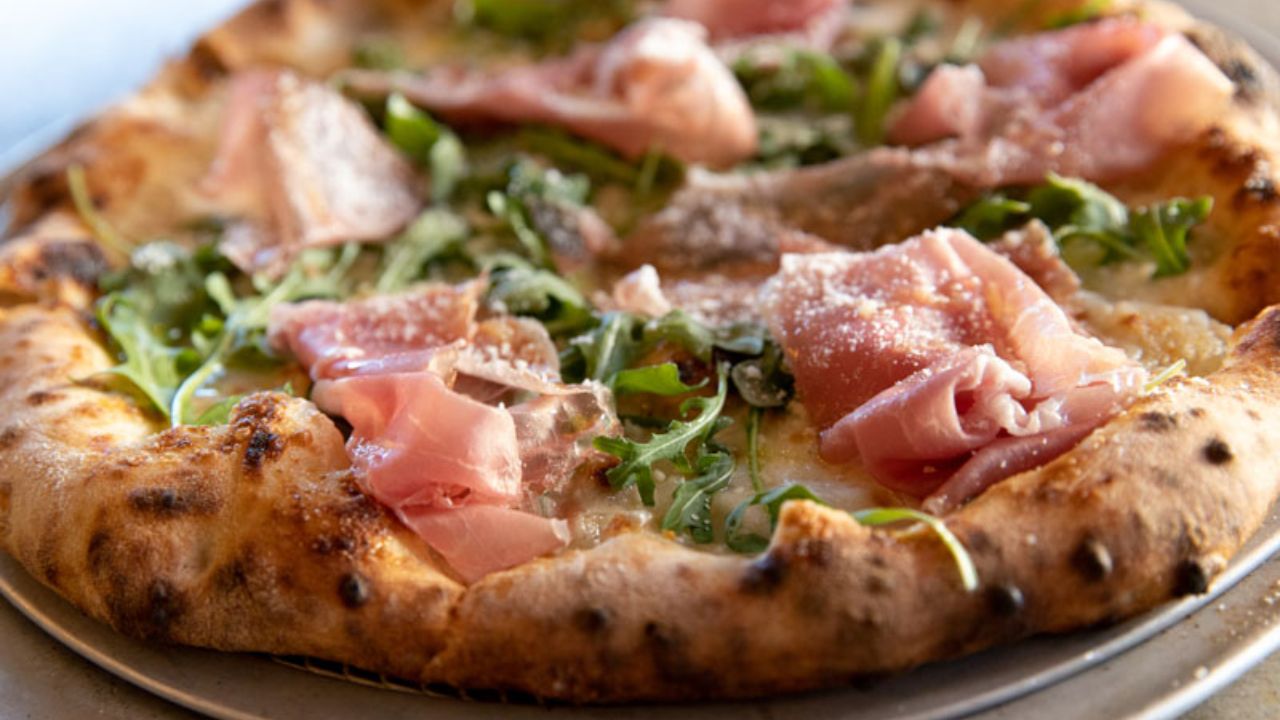 Fresh artisan pizza topped with prosciutto, arugula, and cheese at Montana Nights.