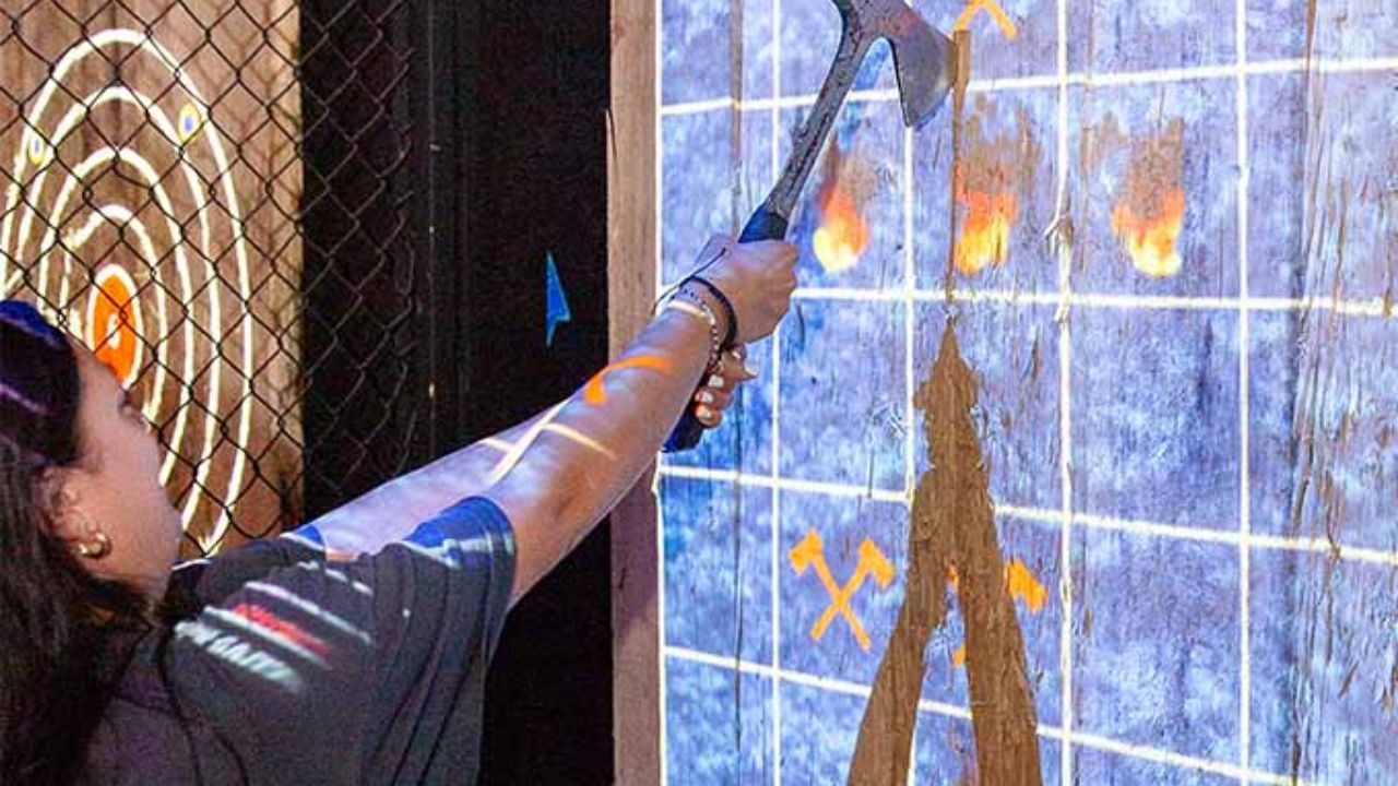 Woman playing an interactive projected axe-throwing game at Montana Nights.