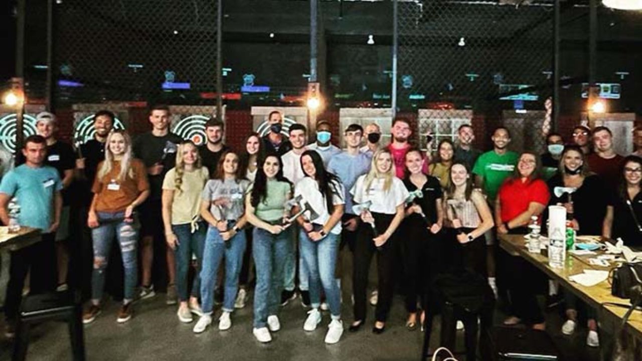 Large group poses in front of axe throwing lanes during a group outing.